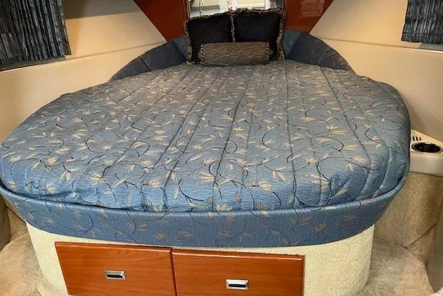 Slide: The Image of 2005 Formula 37 Performance Cruiser cabin with a plush, blue-patterned bed and wooden storage drawers. - 45