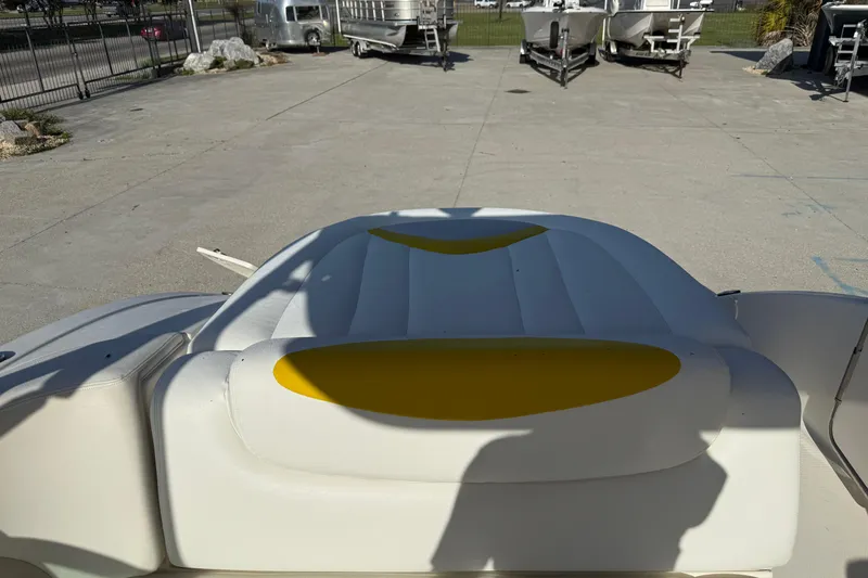 Slide: The Image of 2008 Chaparral 236 SSX boat interior with white and yellow seating, parked outdoors. - 18