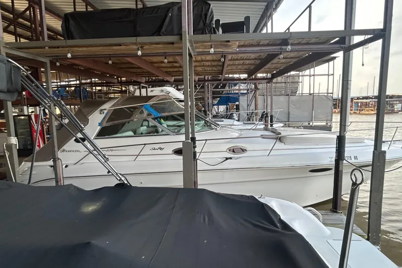 Slide: The Image of 1997 Sea Ray Sundancer 330 docked in a marina, sheltered under a covered structure. - 15