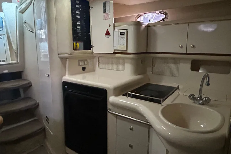 Slide: The Image of 1997 Sea Ray Sundancer 330 yacht interior kitchen with sink, stove, and cabinetry. - 30