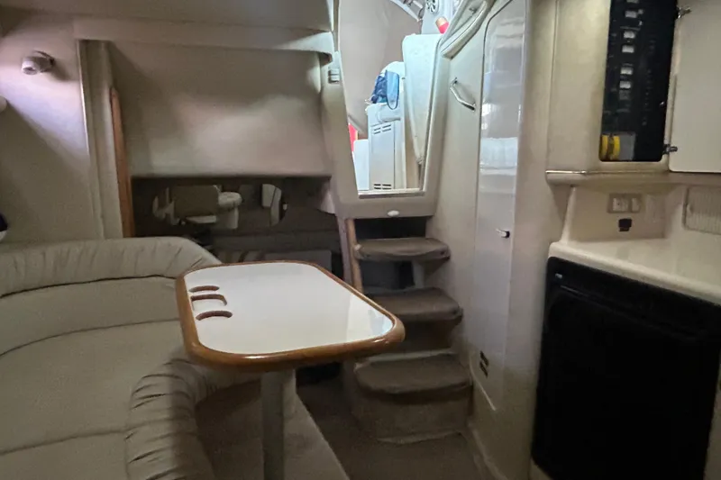 Slide: The Image of Interior of a 1997 Sea Ray Sundancer 330 yacht, featuring a cozy seating area and compact kitchen. - 31