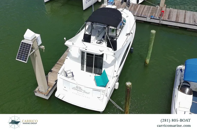 Slide: The Image of 2000 Carver 350 Mariner docked at marina, featuring solar panel and seating area. - 3
