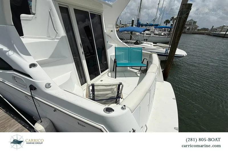 Slide: The Image of 2000 Carver 350 Mariner yacht docked, featuring spacious deck with chairs and marina view. - 8