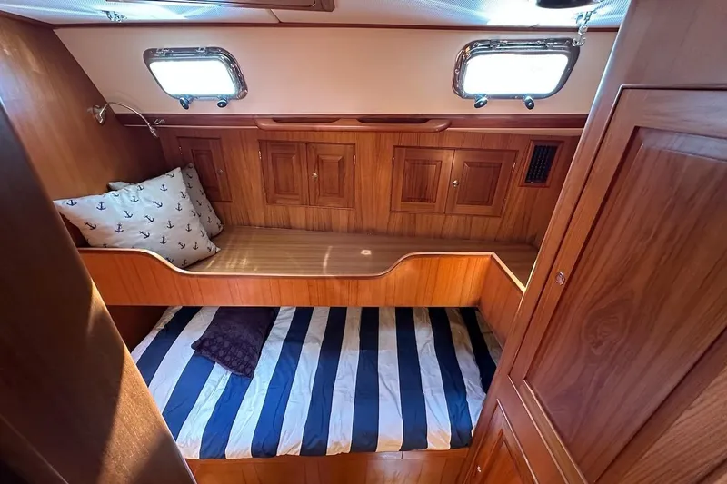Slide: The Image of Cozy cabin interior of 2012 Hylas 56 yacht with wooden finish and striped bedding. - 36