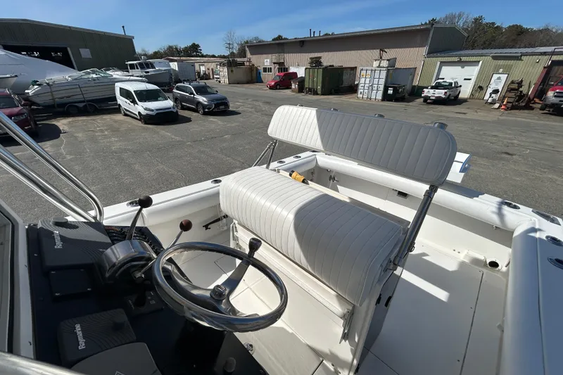 Slide: The Image of 2006 Albin 26 Center Console boat interior with steering wheel and seating in a marina setting. - 16