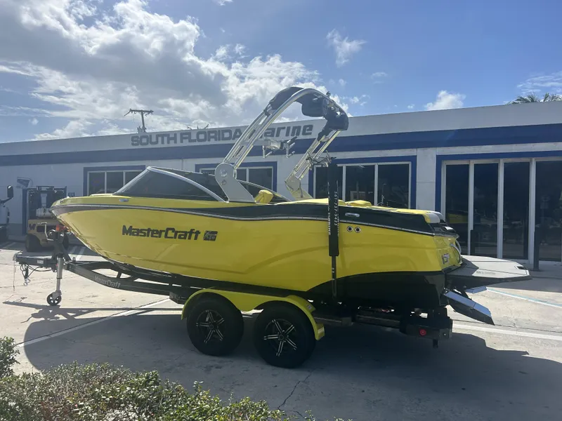 The Image of Yellow 2021 MasterCraft XT21 boat in front of a marine shop. - 0