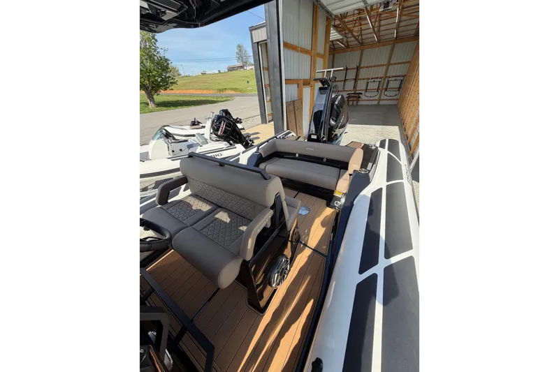 Slide: The Image of 2026 Brig Eagle 8 boat interior with cushioned seating, parked in a wooden shed. - 14