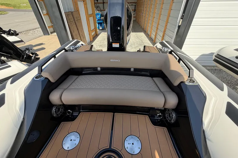 Slide: The Image of 2026 Brig Eagle 8 boat interior with beige seating and wooden deck in a garage. - 16