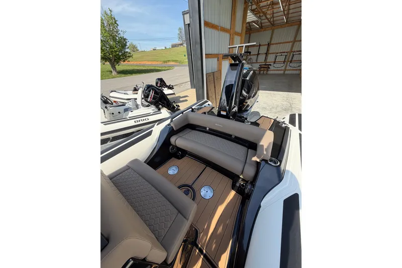 Slide: The Image of 2026 Brig Eagle 8 boat interior with beige seating and wooden deck in a garage. - 17