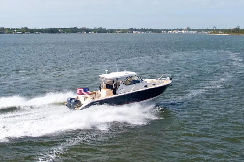 Slide: The Image of 2016 Pursuit OS 325 Offshore boat cruising on open water with American flag. - 10
