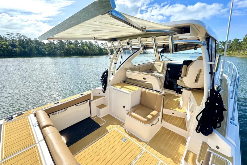 Slide: The Image of 2016 Pursuit OS 325 Offshore boat interior with seating, canopy, and scenic water view. - 12