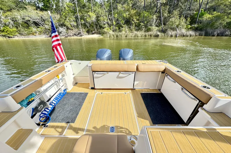 Slide: The Image of 2016 Pursuit OS 325 Offshore boat deck with seating, American flag, and scenic water view. - 16