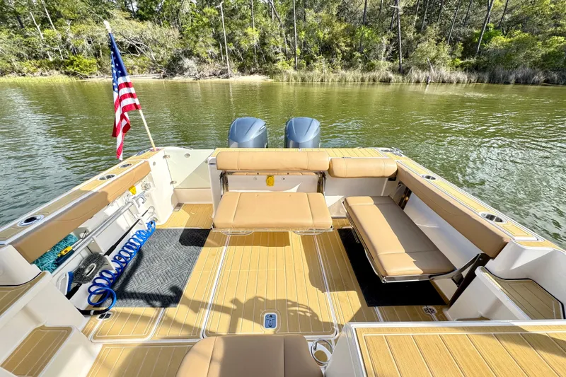 Slide: The Image of 2016 Pursuit OS 325 Offshore boat interior with seating, American flag, and scenic water view. - 17