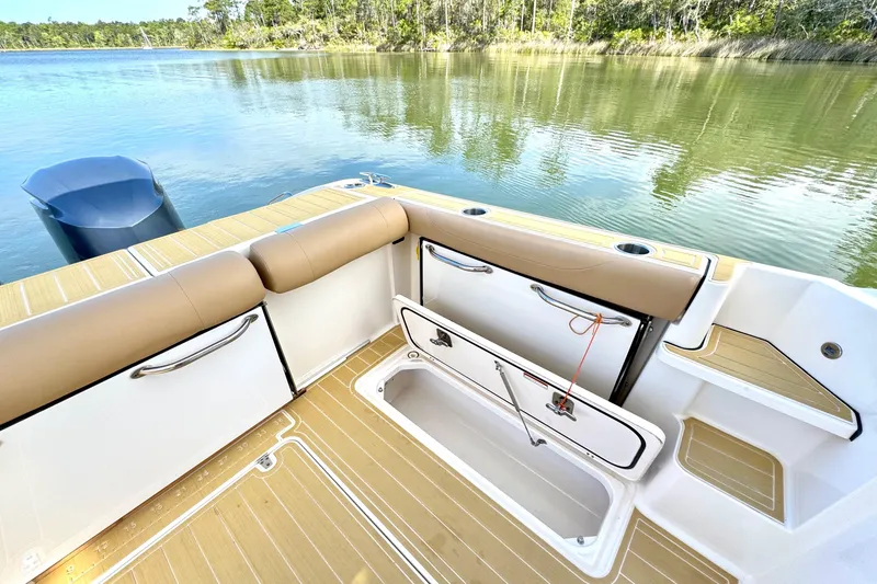 Slide: The Image of 2016 Pursuit OS 325 Offshore boat interior with open storage compartment by the water. - 20