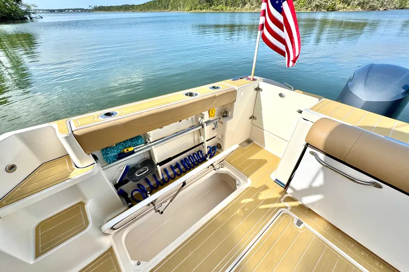 Slide: The Image of 2016 Pursuit OS 325 Offshore boat deck with American flag, overlooking serene water. - 21