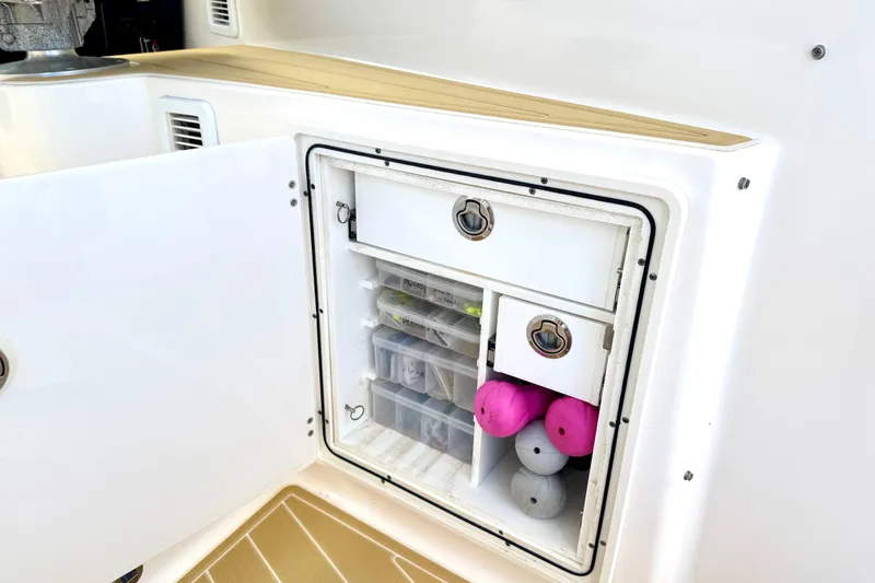 Slide: The Image of Storage compartment on a 2016 Pursuit OS 325 Offshore boat, featuring organized fishing gear. - 23