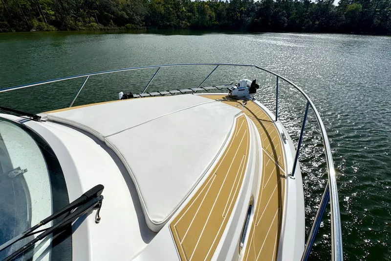 Slide: The Image of 2016 Pursuit OS 325 Offshore boat on a serene lake with lush forest backdrop. - 26