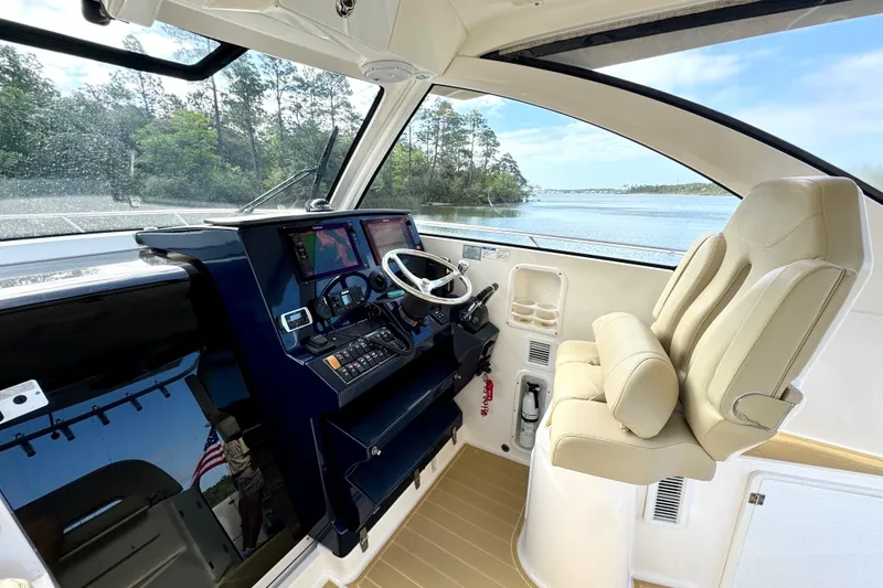 Slide: The Image of 2016 Pursuit OS 325 Offshore helm with dual seats and navigation controls, overlooking serene waters. - 34