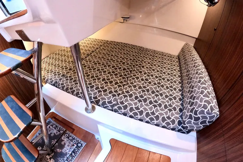 Slide: The Image of 2016 Pursuit OS 325 Offshore cabin interior with patterned bedding and wooden accents. - 41
