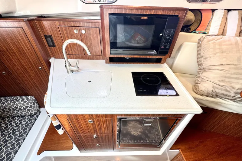 Slide: The Image of 2016 Pursuit OS 325 Offshore boat kitchen with sink, microwave, and stove. - 43