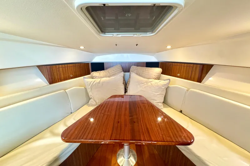 Slide: The Image of 2016 Pursuit OS 325 Offshore cabin interior with wooden table and cushioned seating. - 44