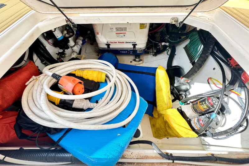 Slide: The Image of 2016 Pursuit OS 325 Offshore engine compartment with generator, cables, and safety equipment. - 48