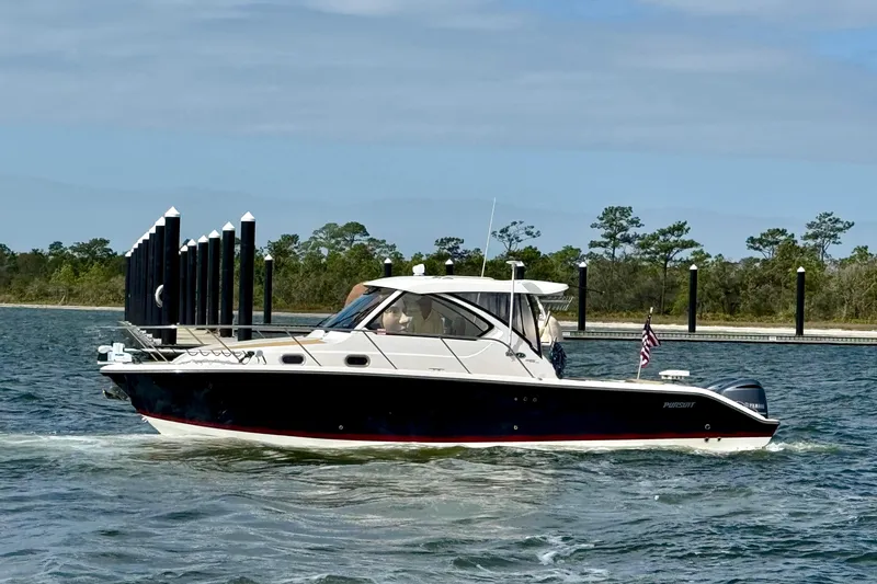 Slide: The Image of 2016 Pursuit OS 325 Offshore boat cruising on a calm lake with trees in the background. - 5