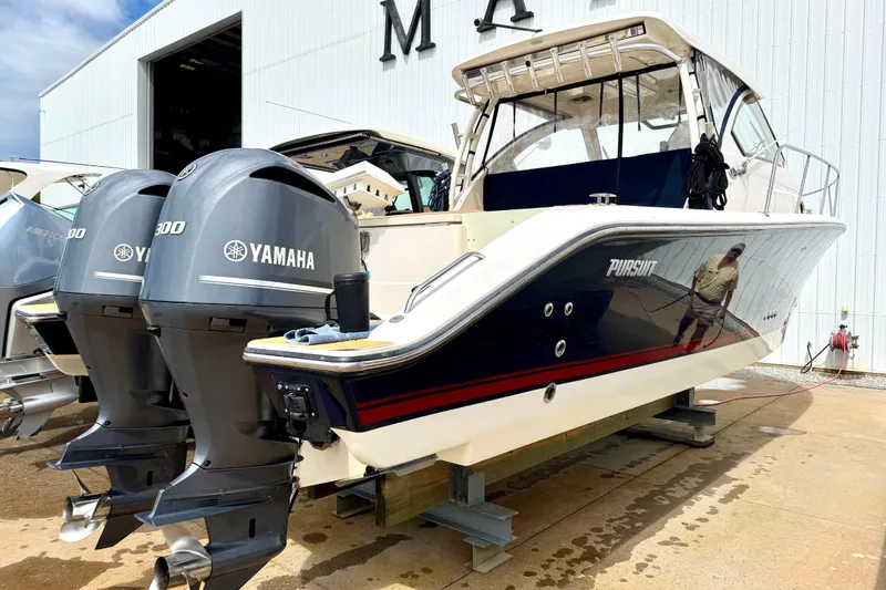 Slide: The Image of 2016 Pursuit OS 325 Offshore boat with twin Yamaha engines, docked outside a warehouse. - 53