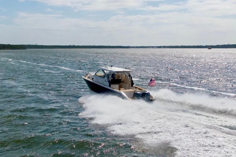 Slide: The Image of 2016 Pursuit OS 325 Offshore cruising on open water with American flag. - 7
