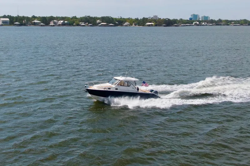 Slide: The Image of 2016 Pursuit OS 325 Offshore cruising on open water with shoreline in background. - 8