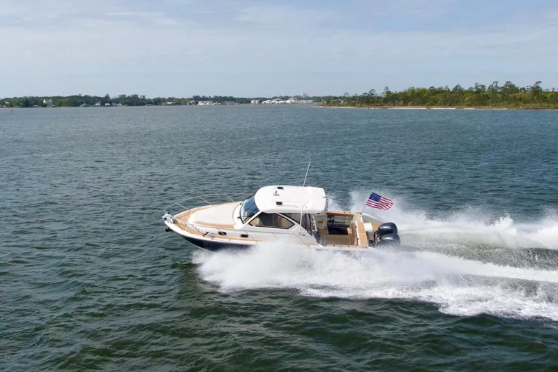Slide: The Image of 2016 Pursuit OS 325 Offshore boat cruising on open water with American flag. - 9