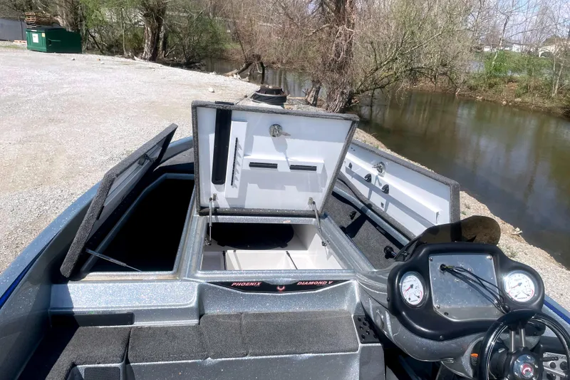 Slide: The Image of 2013 Phoenix 618 Pro boat with open storage compartments by a riverside. - 8