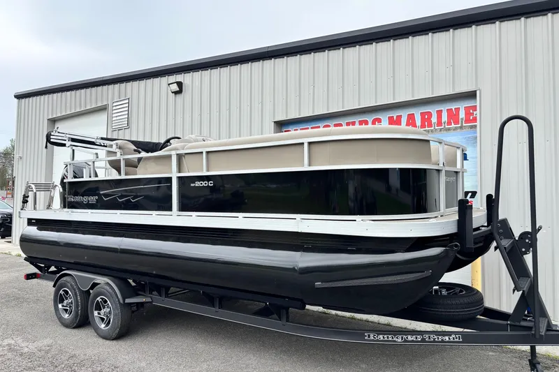 The Image of 2025 Ranger 200C pontoon boat on trailer outside a marine dealership. - 1