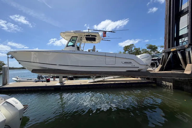 The Image of 2019 Boston Whaler 330 Outrage boat docked by the water under a clear blue sky. - 0