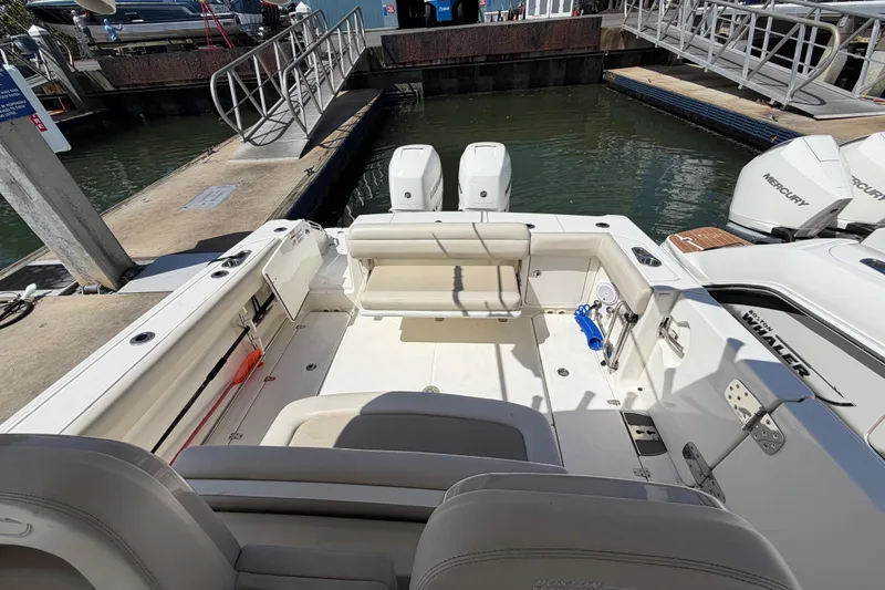 Slide: The Image of 2019 Boston Whaler 330 Outrage boat interior at dock, featuring seating and twin Mercury engines. - 11