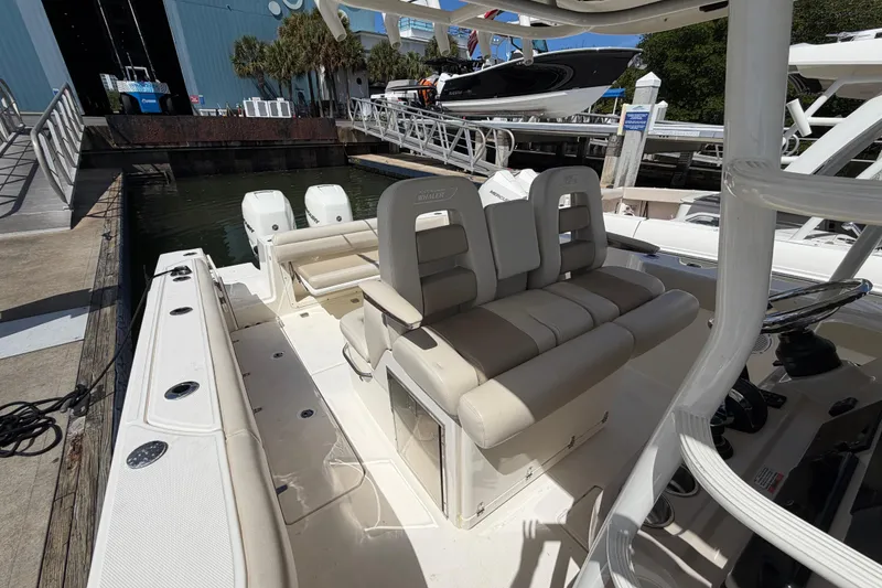 Slide: The Image of 2019 Boston Whaler 330 Outrage boat interior with seating and dual engines at dock. - 15