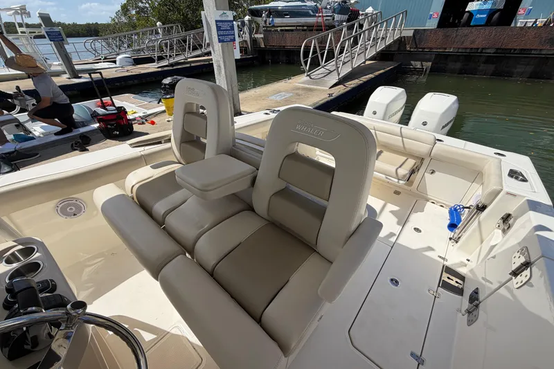 Slide: The Image of 2019 Boston Whaler 330 Outrage boat interior with seating and dock view. - 16