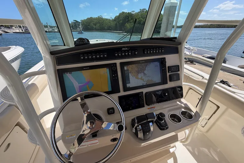 Slide: The Image of 2019 Boston Whaler 330 Outrage helm with navigation screens and controls, docked by the water. - 20