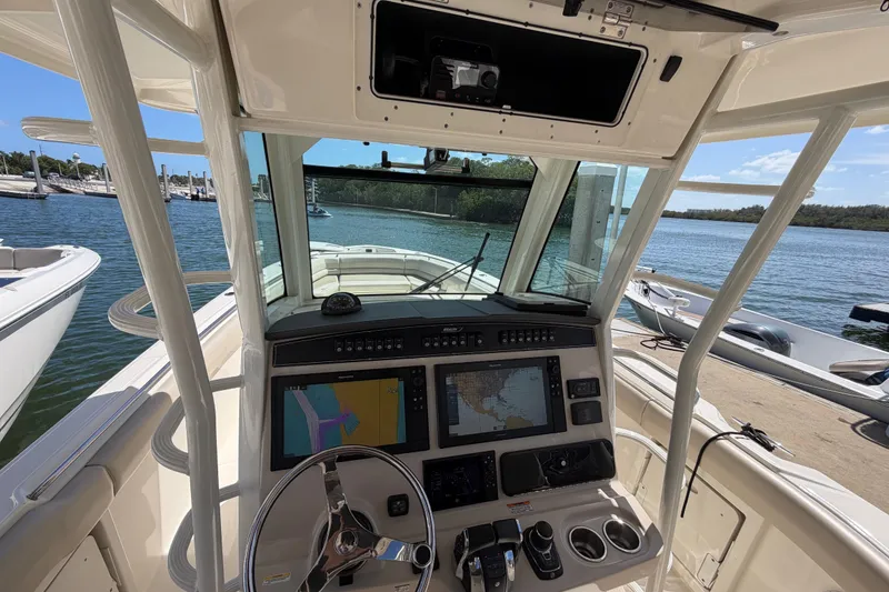 Slide: The Image of 2019 Boston Whaler 330 Outrage helm with navigation screens, docked by the water. - 21