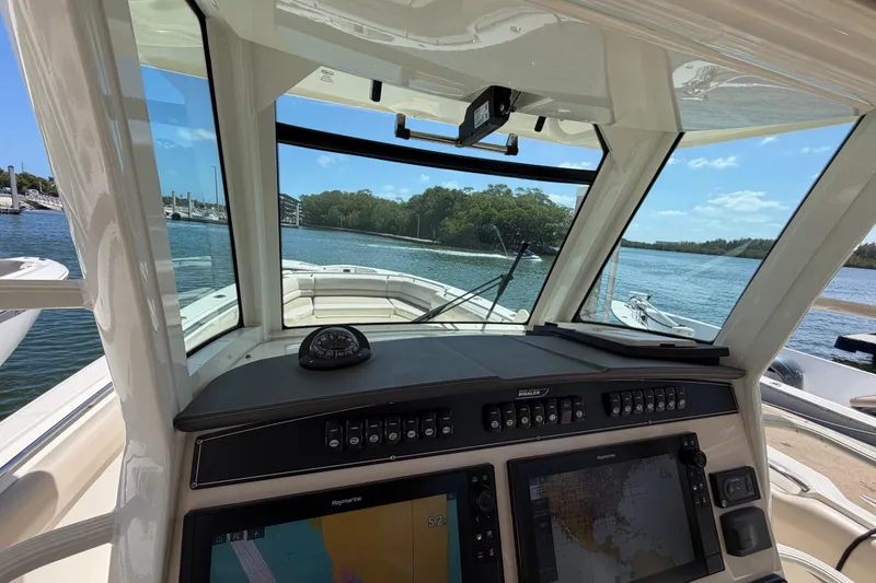 Slide: The Image of 2019 Boston Whaler 330 Outrage helm with navigation screens and scenic water view. - 22