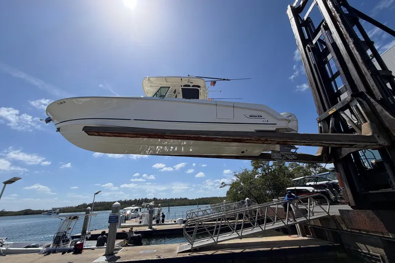 Slide: The Image of 2019 Boston Whaler 330 Outrage boat lifted at marina under clear blue sky. - 3