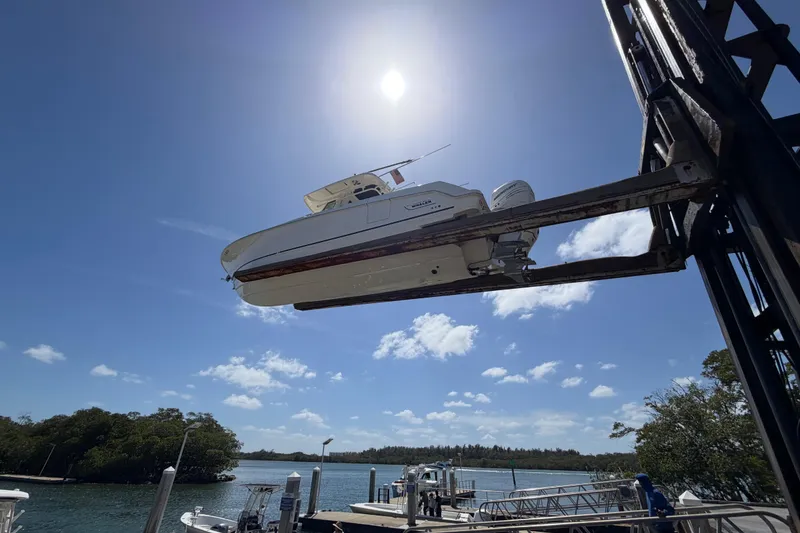 Slide: The Image of 2019 Boston Whaler 330 Outrage boat lifted at marina under sunny sky. - 38