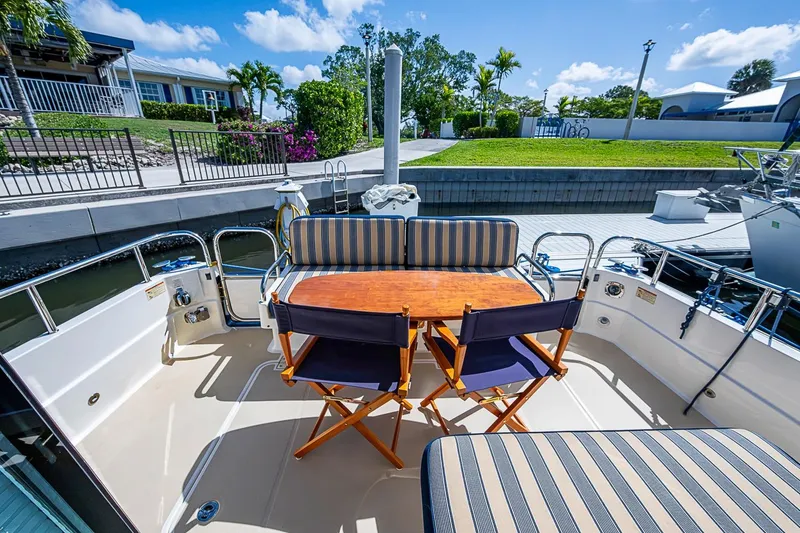 Slide: The Image of 2015 Sabre 38 Salon Express yacht deck with seating and table, docked under blue sky. - 5