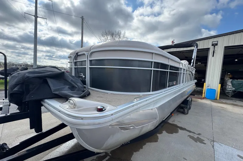 Slide: The Image of 2014 Bennington 2550GSRB pontoon boat on trailer, parked outside a garage under cloudy skies. - 4