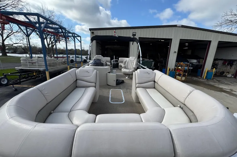 Slide: The Image of 2014 Bennington 2550GSRB pontoon boat with spacious seating, parked near a workshop. - 5