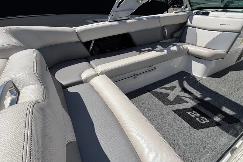 Slide: The Image of 2017 MasterCraft XT23 boat interior with gray seating and branded carpet. - 11