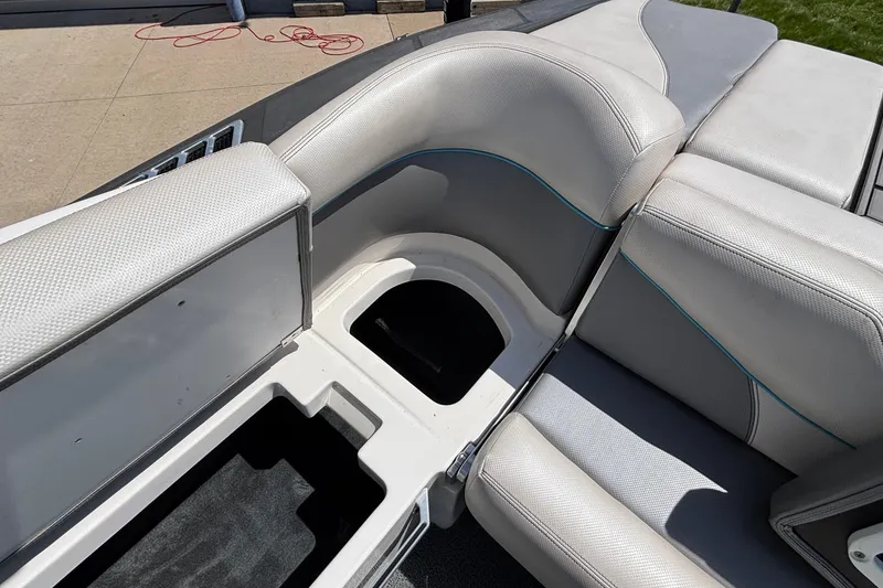 Slide: The Image of 2017 MasterCraft XT23 boat interior with open storage compartments and cushioned seating. - 21