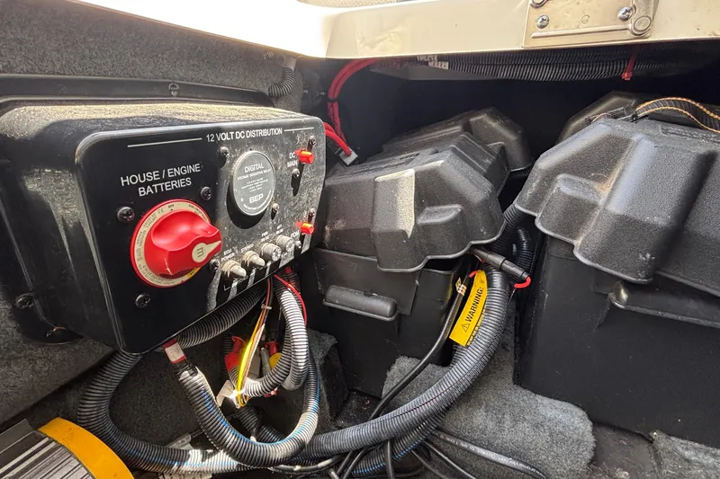 Slide: The Image of 2017 MasterCraft XT23 boat battery compartment with 12V DC distribution panel. - 23