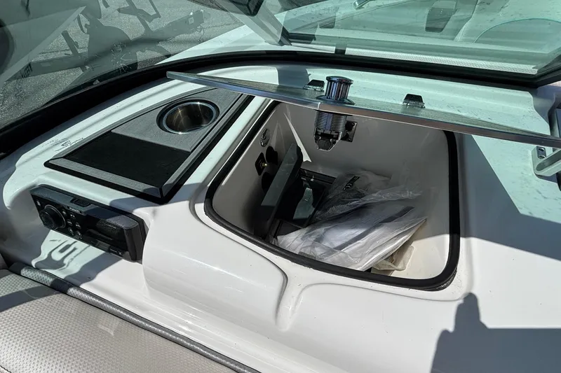 Slide: The Image of 2017 MasterCraft XT23 boat storage compartment with cup holder and audio controls. - 42