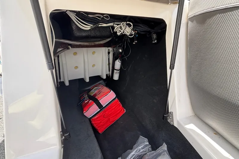 Slide: The Image of Storage compartment of a 2017 MasterCraft XT23 boat with a red bag and equipment. - 48